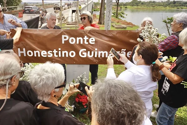 Pessoas ao redor de placa marrom com nome de ponte