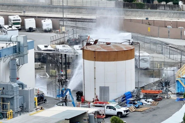 Foto colorido de equipes de emergência tentando resfriar tanque químico - Metrópoles