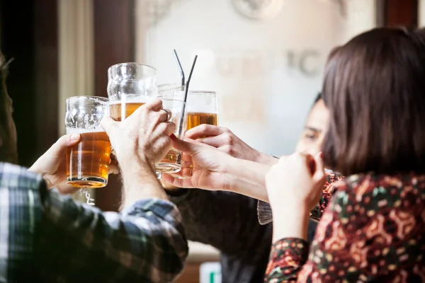 Um grupo de amigos brindando com canecas de cerveja em um pub
