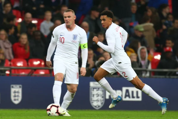 Foto colorida de Rooney e Alexander-Arnold, atuando juntos pela seleção inglesa - Metrópoles