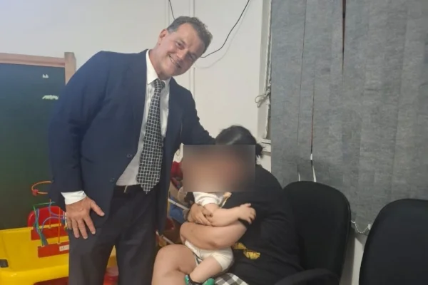 Imagem colorida de advogado ao lado de mãe autista com a filha recém resgatada. Metrópoles