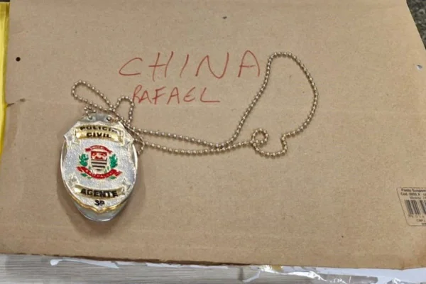 Imagem colorida mostra um falso distintivo policial sobre papel pardo com as palavras China e Rafael escritas