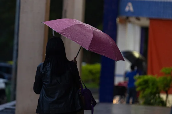 imagem colorida de pessoa com guarda-chuva em plena chuva