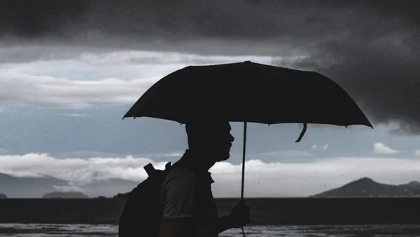Imagem colorida de homem segurando um guarda-chuva frente fria - Metrópoles