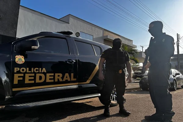 Imagem colorida mostra agentes da PF perto de viatura preta