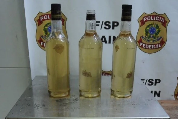 Imagem colorida de garrafas contendo cocaína em seu interior. Metrópoles