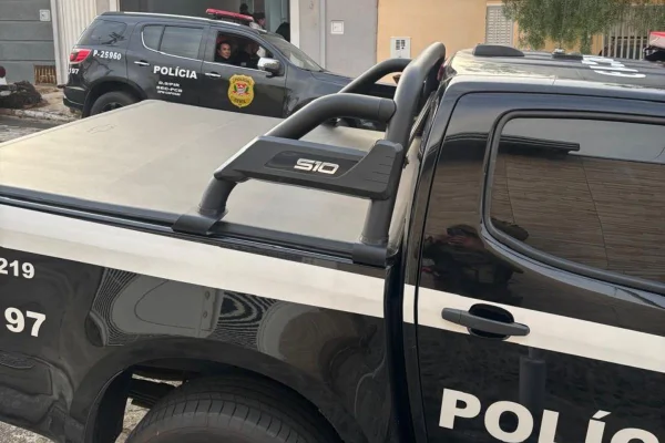 Foto colorida de viaturas em frente a um imóvel alvo de operação da Polícia Civil de São Paulo.