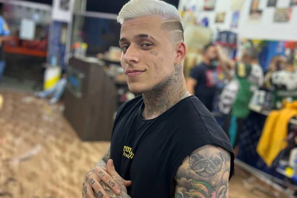 homem posa de cabelo platinado e regata preta