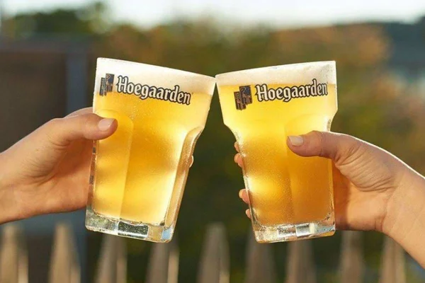 Duas mãos brindando com corpos de cerveja