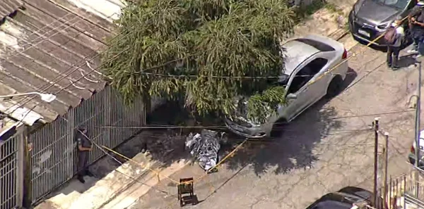 Imagem aérea de corpo de homem morto com chave de fenda caído na rua coberto por manta metálica - Metrópoles