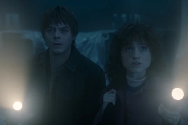 Imagem colorida com filtro azul de Charlie Heaton como Jonathan Byers e Natalia Dyer como Nancy Wheeler em Stranger Things - Metrópoles