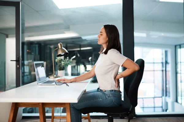 Imagem mostra mulher trabalhando sentada com dor nas costas - Metrópoles