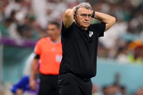 Homem velho e de cabelo branco, usando roupas pretas e colocando as mãos na cabeça em sinal de decepção após ter sido eliminado da Copa do Mundo no catar - técnico do méxico