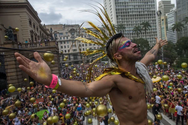 imagem colorida mostra homem de braços abertas em cima de trio elétrico. ao fundo, multidão acompanha bloco de carnaval - metrópoles