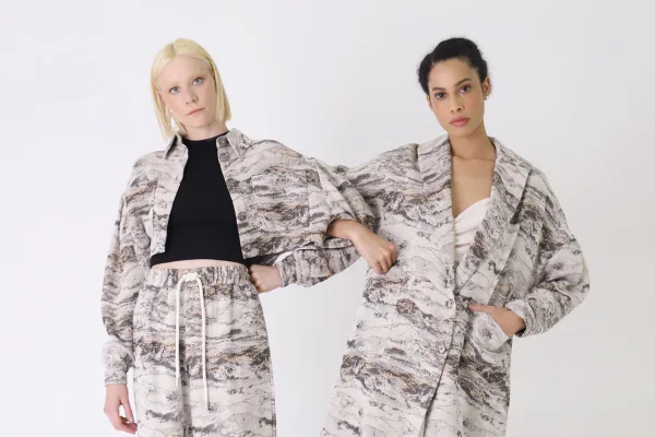 Duas modelos de braços dados usando looks com estampa jacquard em tons de cinza - Metrópoles