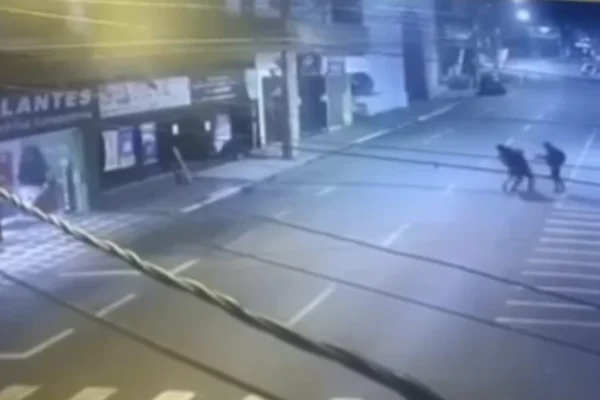 Imagem colorida de dois indivíduos abordando um homem no meio da rua - Metrópoles