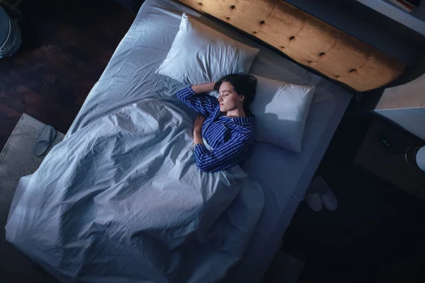 mulher adormecida deitada de lado na cama Acordar de madrugada não é bom sinal