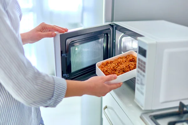 Aquecendo um recipiente de comida no moderno forno de micro-ondas - Metrópoles