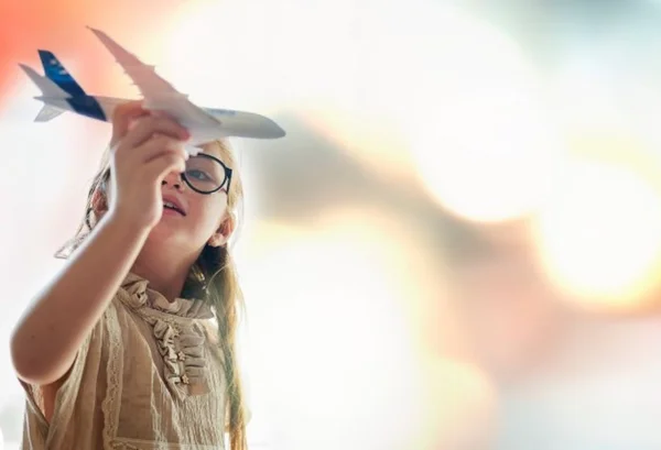 Menina segurando avião de brinquedo na mão