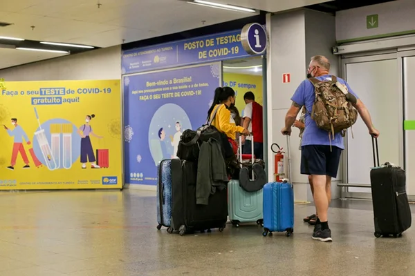 Homem de costas andando com malas em aeroporto