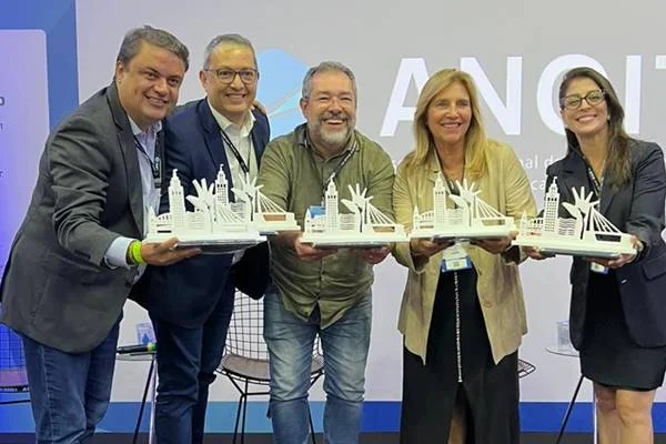 Fotografia colorida de cinco pessoas segurando troféus