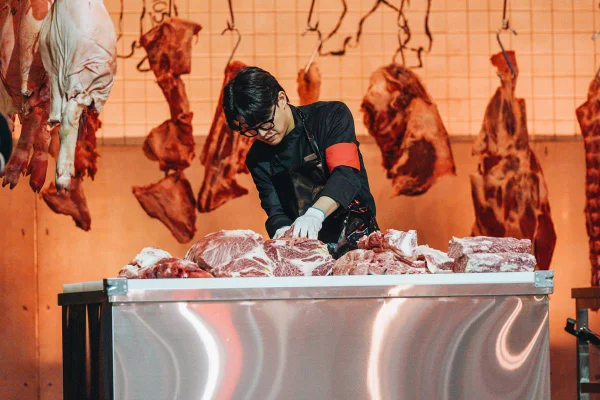 Homem cortando carne em um balcão - Metrópoles
