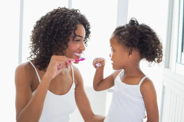 Mãe e filha escovando os dentes