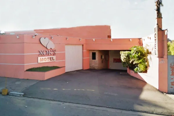 Fachada de motel com letreiro escrito Motel Xok's e paredes em tons de rosa salmão