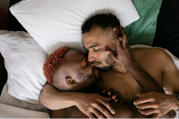 Dois homens deitados na cama se beijando