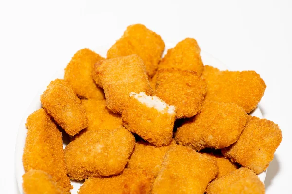 Foto colorida de nuggets de frango empilhados - Metrópoles