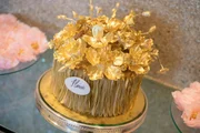 Para o bolo, tons de dourado e decorações florais sofisticadas