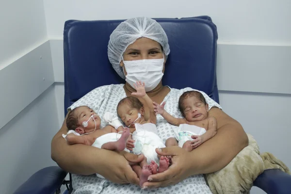 Mulher segurando seus três filhos