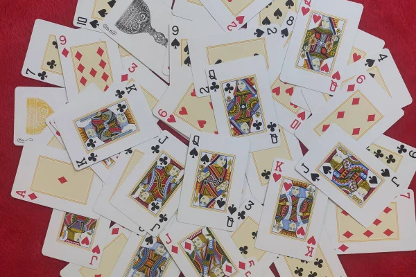 Imagem colorida de cartas de baralho sobre um pano vermelho - Metrópoles