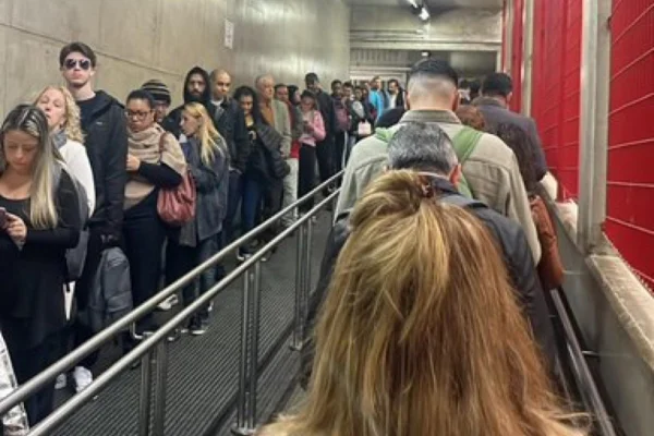 Imagem colorida de fila para entrar em estação de metrô