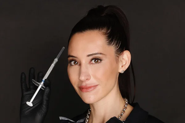 Mulher sorrindo para a foto com uma seringa na mão - Metrópoles