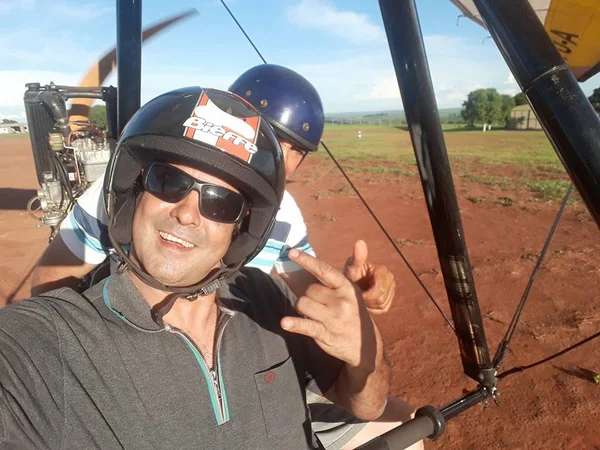 imagem colorida mostra homem, um instrutor de asa delta, em equipamento de asa delta. ele é branco, usa capacete e óculos preto e está com uma blusa cinza. outro homem está atrás dele, também de capacete; ele sofreu uma queda de parapente e está desaparecido - metrópoles