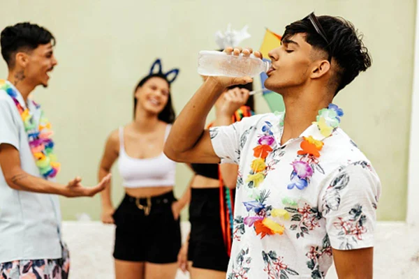 Rapaz bebendo água durante bloco de carnaval na rua