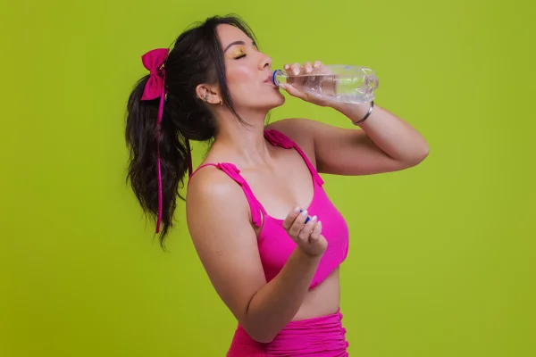 Foto colorida de mulher, com fantasia de Carnaval, tomando água - Metrópoles