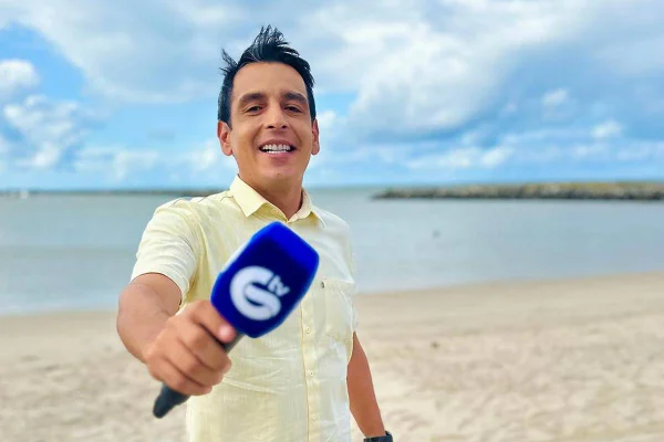 foto colorida de homem branco segurando microfone com praia ao fundo - metrópoles