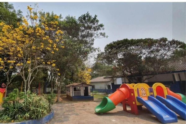 Foto colorida mostra área aberta com parque de escola sob o sol - Metrópoles