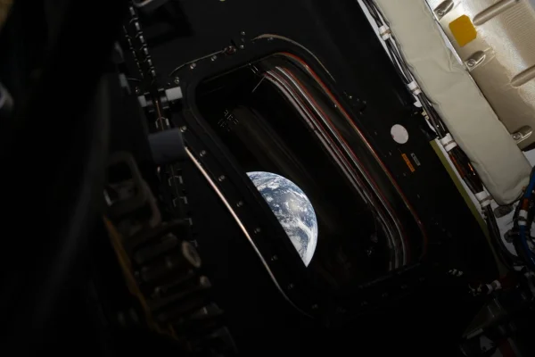 Imagem mostra a Terra vista do espaço por uma escotilha - Metrópoles