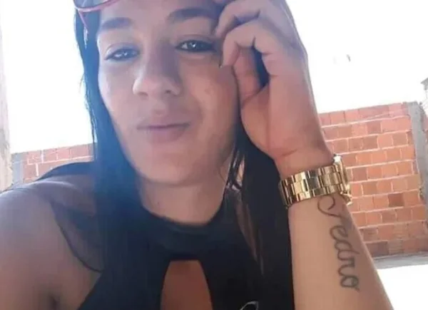 Selfie colorida mostra mulher de cabelo preto com a cabeça apoiada na mão. Ela tem um relógio dourado e uma tatuagem escrito "Pedro"