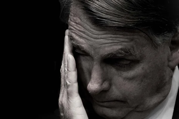 Imagem em preto e branco mostra o ex-presidente Jair Bolsonaro com a mão no rosto - Metrópoles