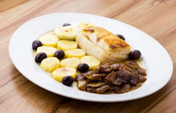 prato com bacalhau, cebola caramelizada, batatas, azeitonas pretas e ovos cozidos