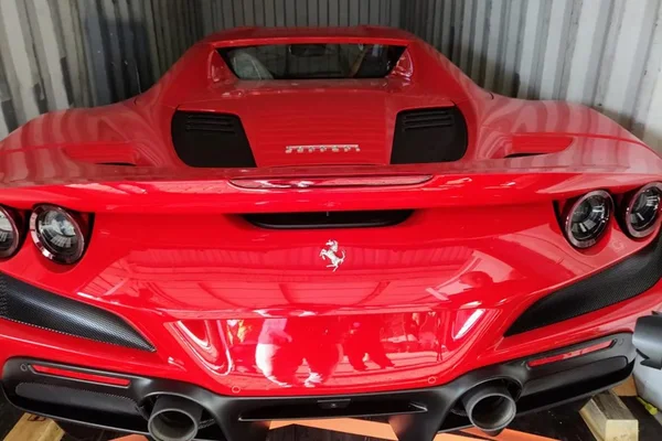Imagem mostra carro do tipo Ferrari em um contêiner. o veículo é da cor vermelha - Metrópoles
