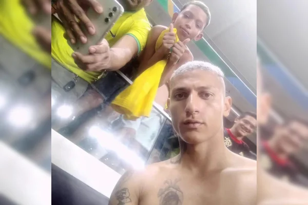 Imagem colorida de homem tiradno selfie com menino que está segurando camisa amarela - Metropoles