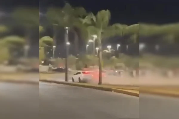 Imagem colorida de dois carros se acidentando em uma pista com árvores verdes ao redor