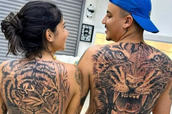Imagem mostra mulher e homem com tatuagem de tigre nas costas - Metrópoles
