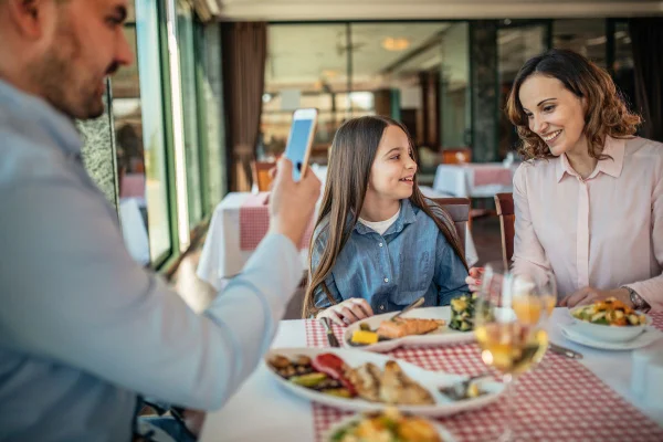 Foto colorida de família almoçando em restaurante