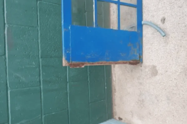 Imagem colorida de uma porta de metal azul caída no chão - Metrópoles